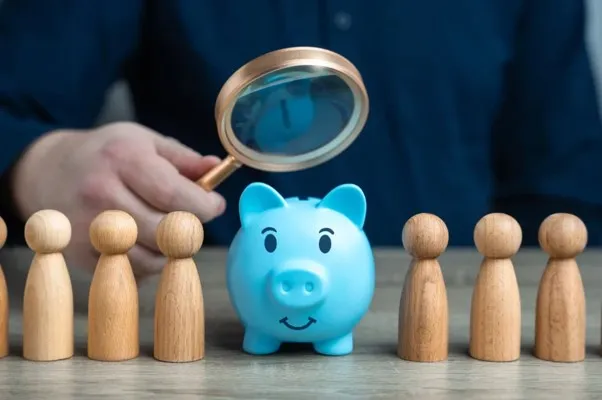 Alcancía de cerdito para hacer referencia a la evaluación de estudios socioeconómicos monterrey Una alcancía de cerdito color azul, unas figuras alrededor, una lupa encima de la alcancía haciendo referencia a los estudios socioeconómicos monterrey
